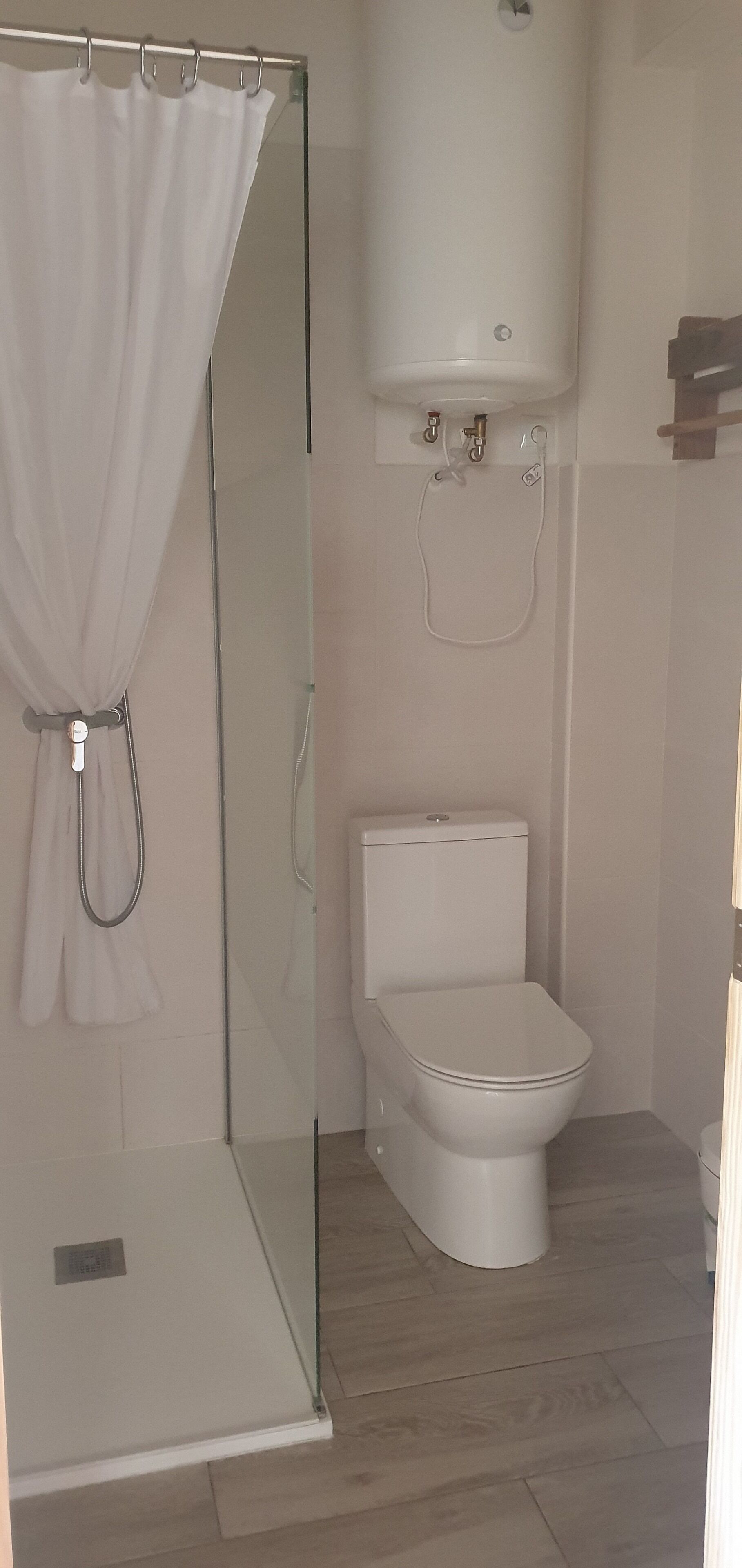 Un baño con cabina de ducha de vidrio, inodoro y bañera blanca.