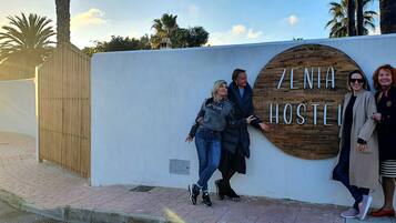 A sign for 'ZENITH HOSTEL' with a wooden background and a white wall.