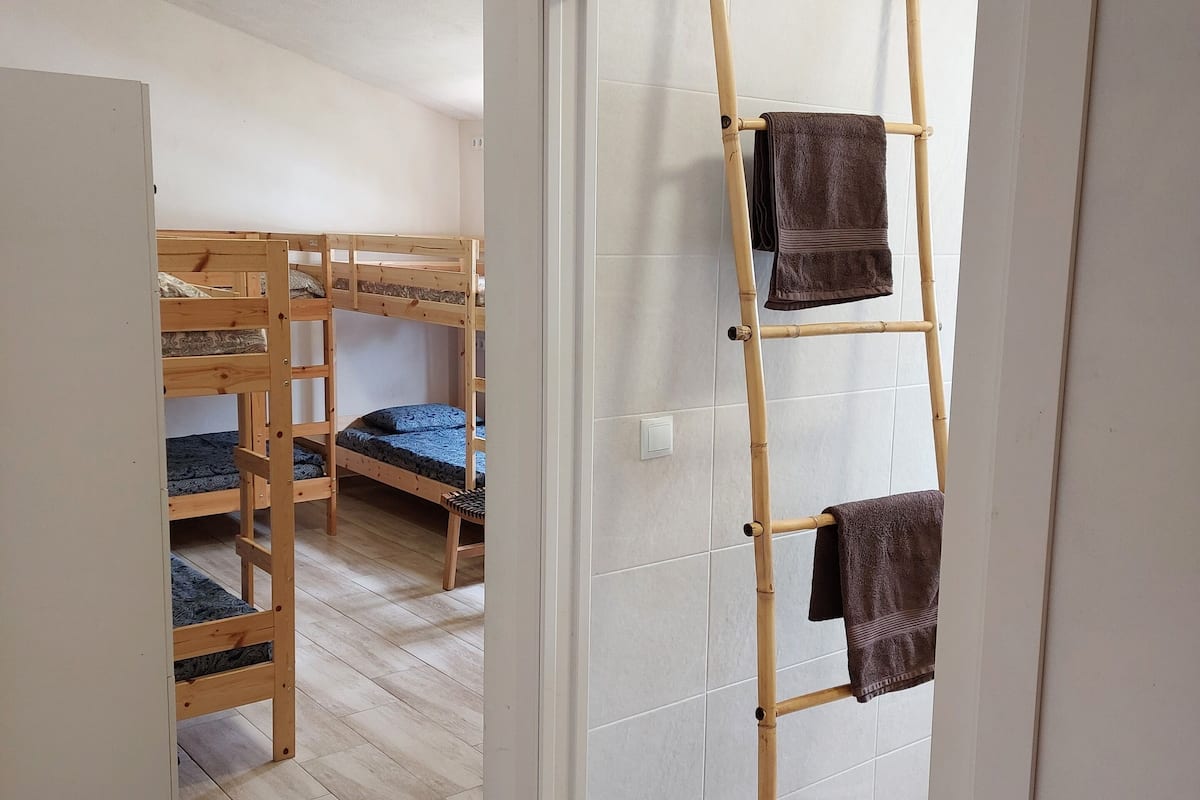 Una habitación con literas, una escalera y una puerta que da a otra habitación.