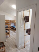 Una habitación con literas, una escalera y una puerta que da a otra habitación.