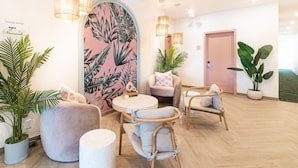 A modern lounge area with a round table, two chairs, and a large potted plant. - Hôtel Le Rosay (Venise-en-Quebec)