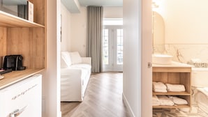 A modern hotel room with a wooden desk, a bed, a bathroom with a marble sink, and a view of the outside. - Hôtel Le Rosay (Venise-en-Quebec)