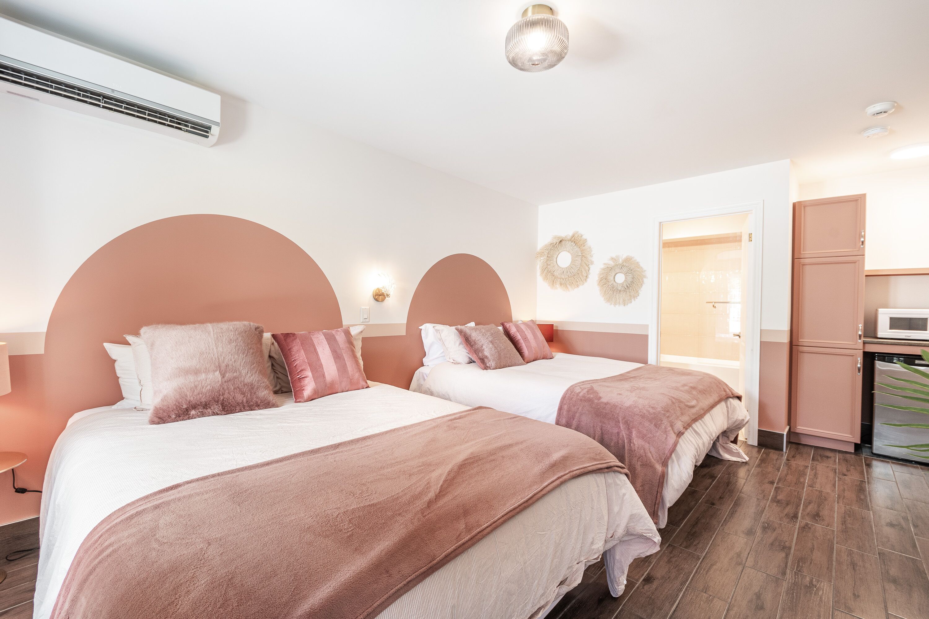 Hotellihuone, jossa on kaksi sänkyä, pieni keittiö ja kylpyhuone.