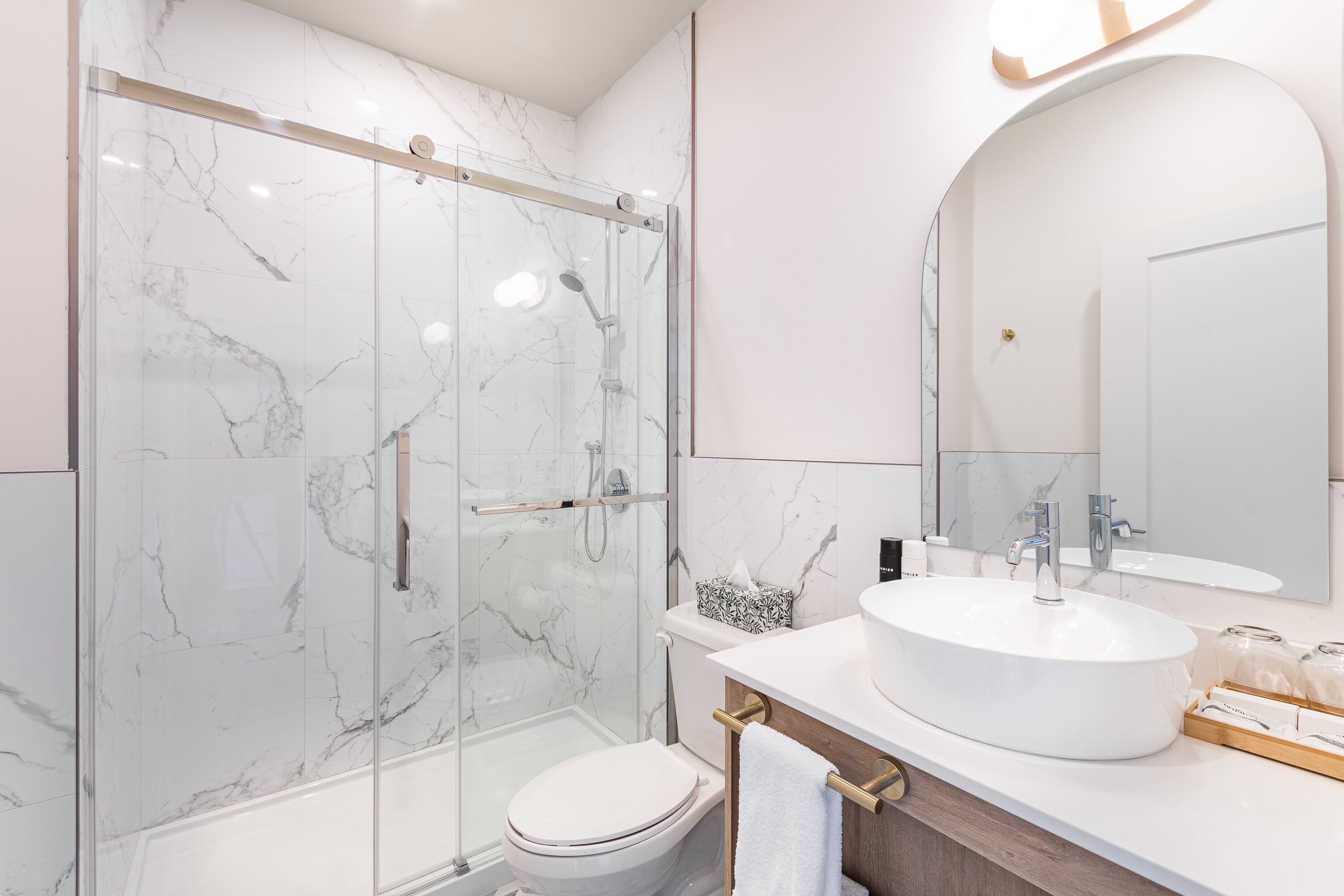 Une salle de bain moderne avec une douche à parois de verre, un lavabo blanc et un grand miroir.