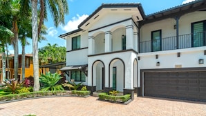 A two-story house with a white facade, a balcony, and a garage. - Tropical Paradise deluxe villa (Miami)