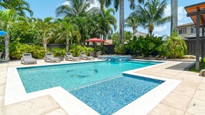 A rectangular swimming pool with a tiled deck, surrounded by lounge chairs and palm trees. - Tropical Paradise deluxe villa (Miami)