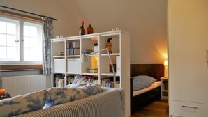 Une pièce chaleureuse avec un canapé à rayures, une bibliothèque, un lit et un radiateur.
