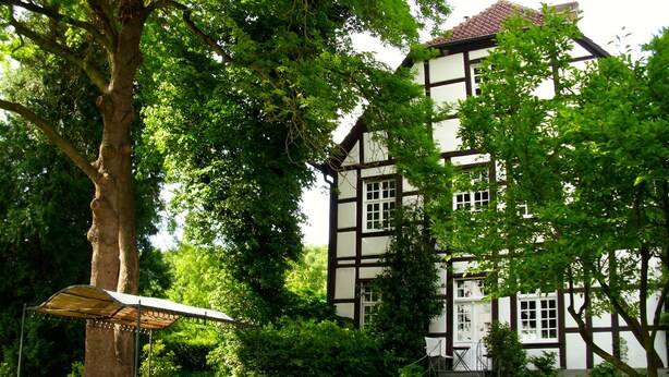 Une maison traditionnelle à colombages, dotée d’un jardin bien entretenu, d’un banc en bois et d’une pergola.