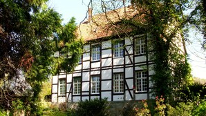 Un bâtiment traditionnel à colombages, doté d’un jardin et d’un petit étang.