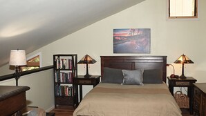 Quarto com uma cama grande, duas mesas de cabeceira, uma estante e uma janela com vista.