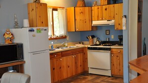 A kitchen with wooden cabinets, a refrigerator, a stove, and a microwave. - 01) The Fishing Lodge (Bayfield)