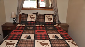 Una cama con colcha de estampados de animales, flanqueada por dos almohadas con diseños similares.