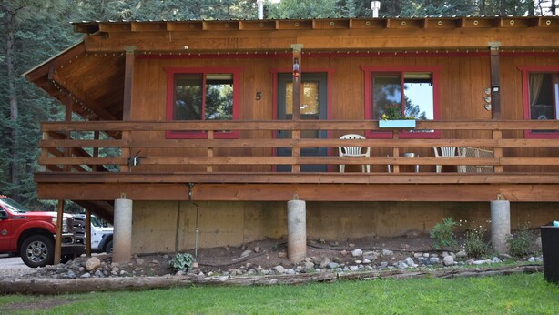 A wooden cabin with a balcony, numbered 5, featuring a simple, rustic design. - 0005) The Wolf Cabin (Bayfield)