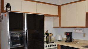 A compact kitchen with a stainless steel refrigerator, a stove, a dishwasher, and wooden cabinets. - 0005) The Wolf Cabin (Bayfield)
