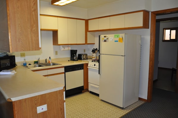Functional kitchen with a refrigerator, oven, microwave, sink, and coffee maker.