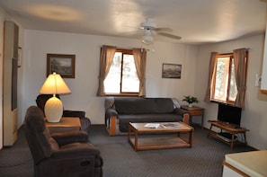 Relax in this inviting living room with a sofa, recliner, and coffee table, featuring a TV and ceiling fan.