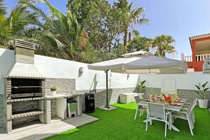 An outdoor patio with a barbecue grill, dining table, and chairs. - Casa Gerard (Costa del Silencio)