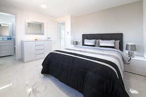 A modern bedroom with a large bed, a bedside table with a lamp, a wardrobe, and a mirror. - Casa Gerard (Costa del Silencio)