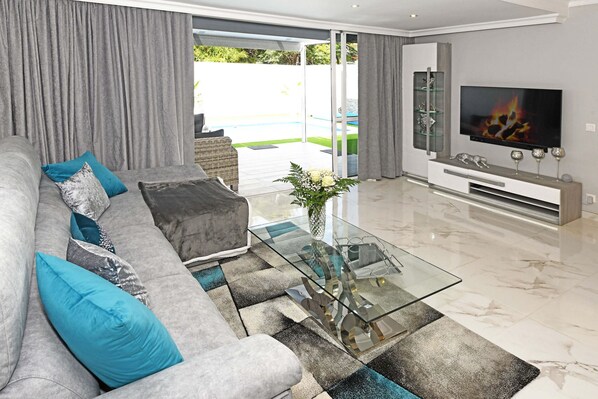 A modern living room with a sofa, glass coffee table, and a flat-screen TV.