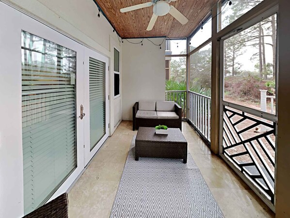 A balcony with a sofa, a small table, and a ceiling fan.