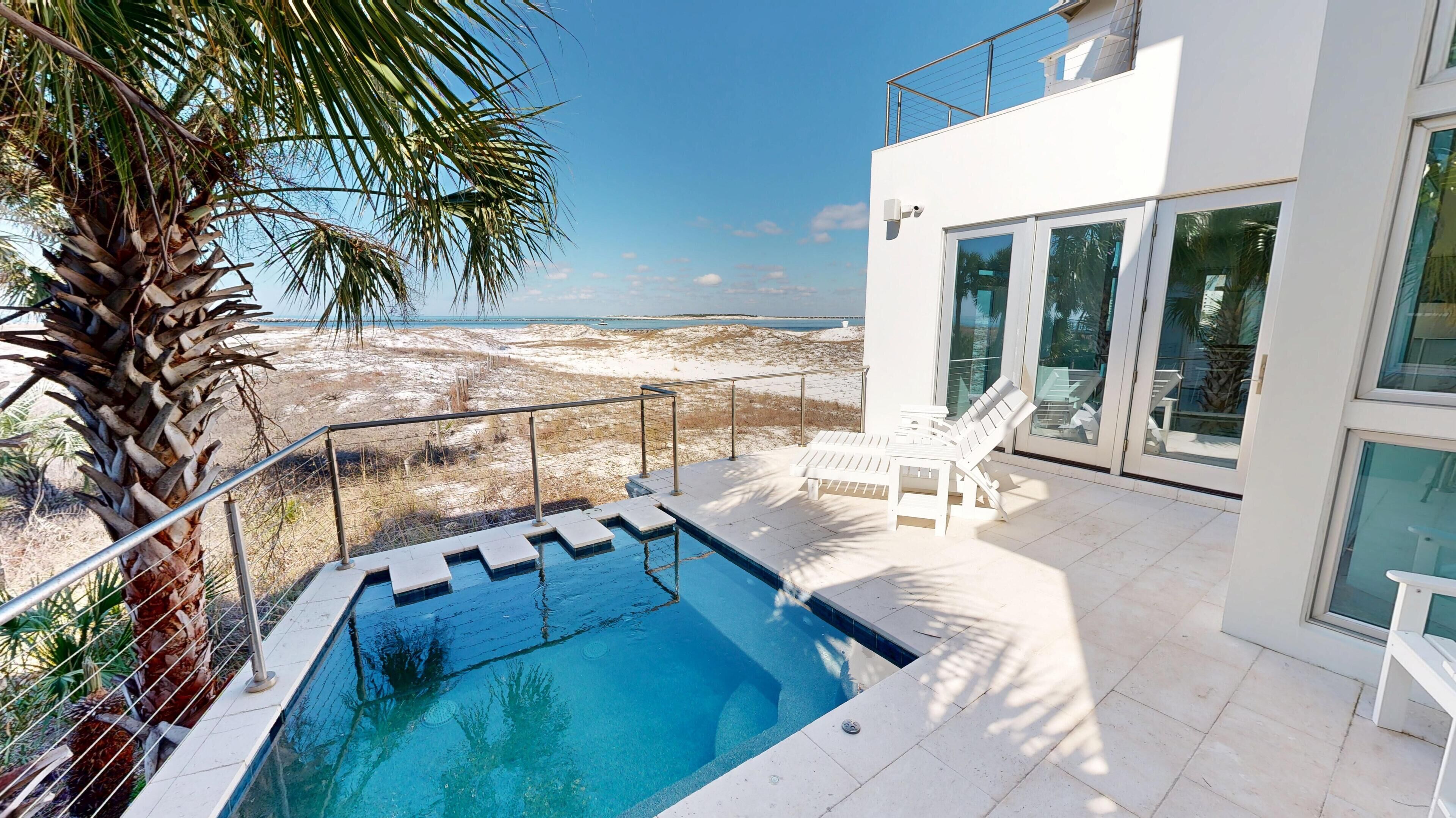 A modern outdoor pool area with a clear view of the beach and ocean.