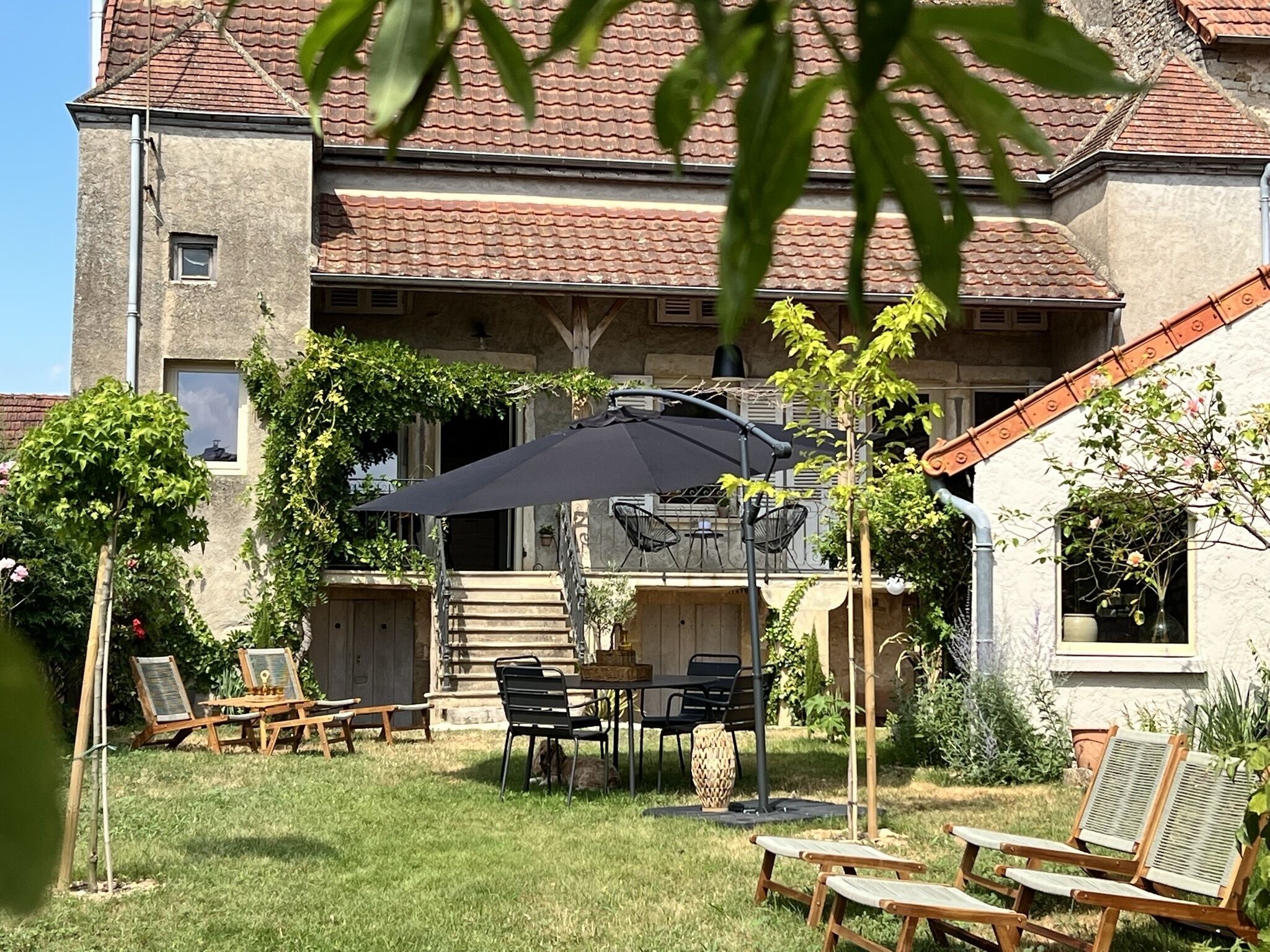 En gårdhave med udendørs siddepladser, et bord og en stor parasol.