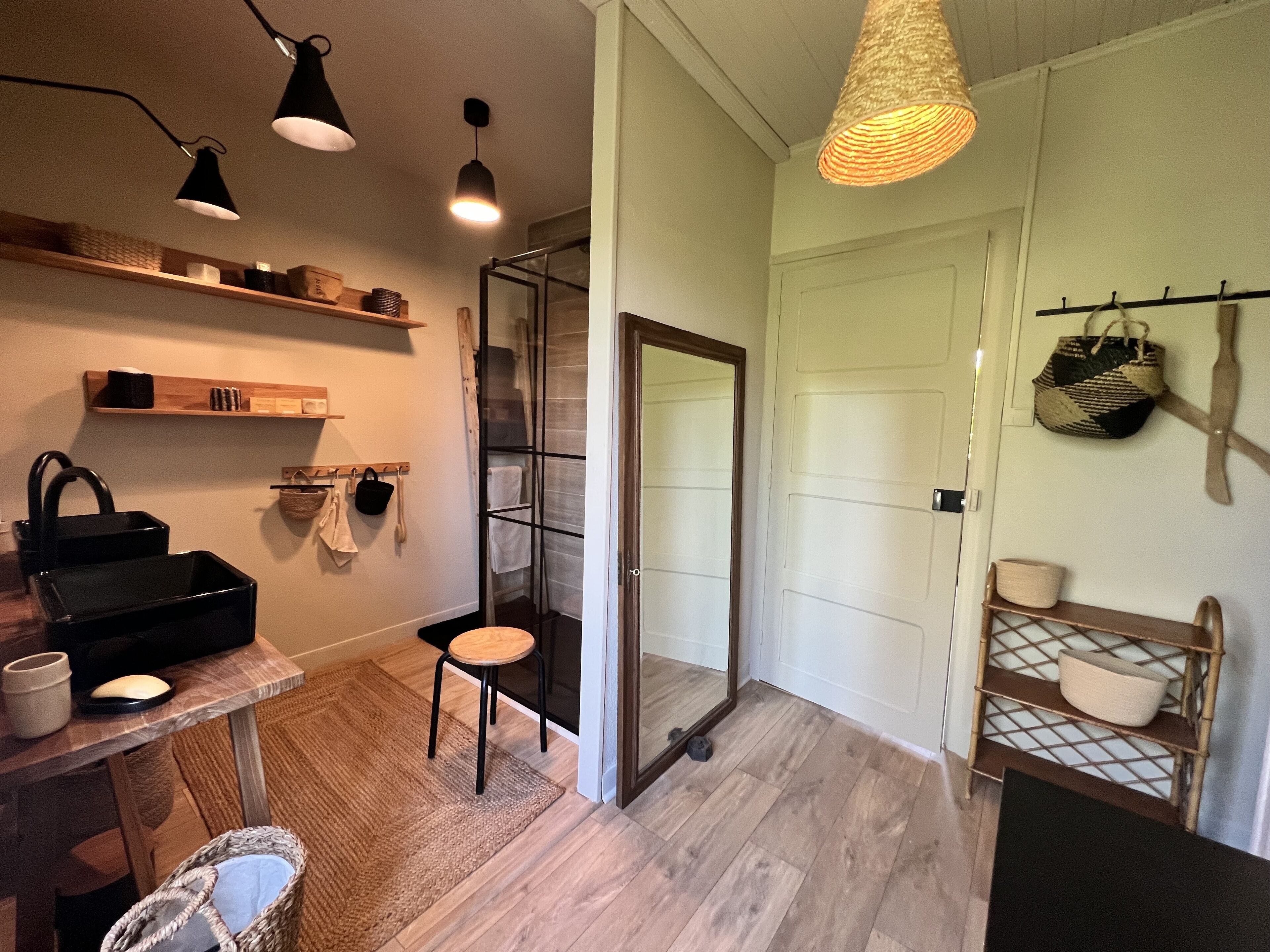 Ein modernes Badezimmer mit Glasdusche, Holzböden und einem kleinen Hocker.