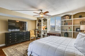 A bedroom with a bed, a ceiling fan, a TV, a dresser, and built-in shelving with various items. - DP 202C Recently renovated 2 bedroom condo near Destin Harbor and amazing views. (Destin)