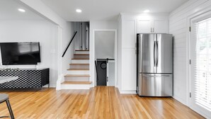 Eine moderne Küche mit einem Edelstahl-Kühlschrank, Holzböden und einer Treppe, die zu einer zweiten Etage führt.
