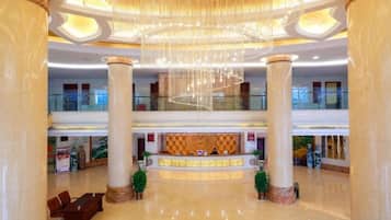 Eine großzügige Lobby mit einer Rezeption, hohen Säulen und einem Chandelier.