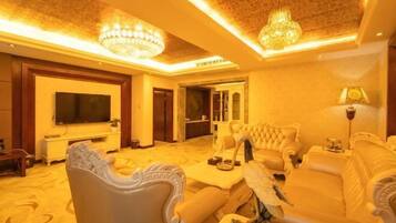 A luxurious living room with ornate furniture, a television, and a chandelier.