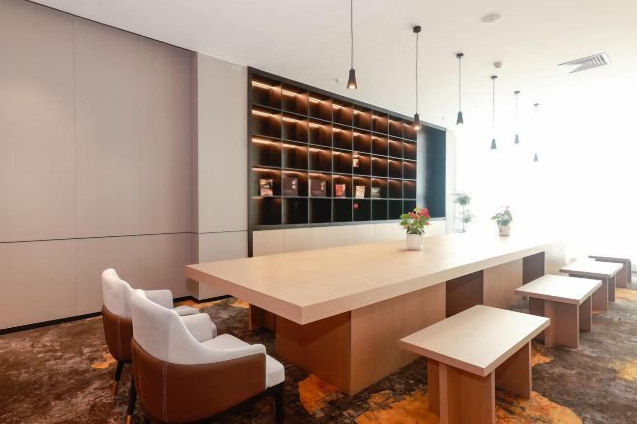 Ein modernes Interieur mit einem langen Tisch, Sitzgelegenheiten und einem wandmontierten Regal mit Gegenständen.