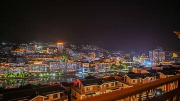 A nighttime cityscape with illuminated buildings and a river reflecting the lights.