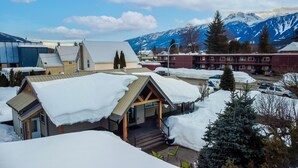 Un hotel con un espacio exterior cubierto, un telón de fondo de montañas y paisajes nevados.