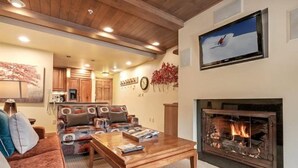 A cozy living room with a fireplace, a television mounted above it, and a sofa with cushions.