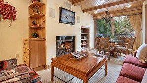 A cozy living room with a fireplace, wooden furniture, and a television.