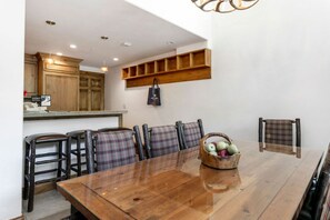 A dining area with a wooden table, plaid chairs, and a basket of apples. - 3 Bedroom in Lionshead Village at The Antlers (Vail)