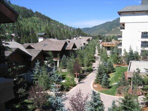 A resort with multiple chalet-style buildings, a central pathway, and a backdrop of forested hills.