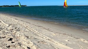 Una playa con cielos azules despejados y aguas tranquilas.
