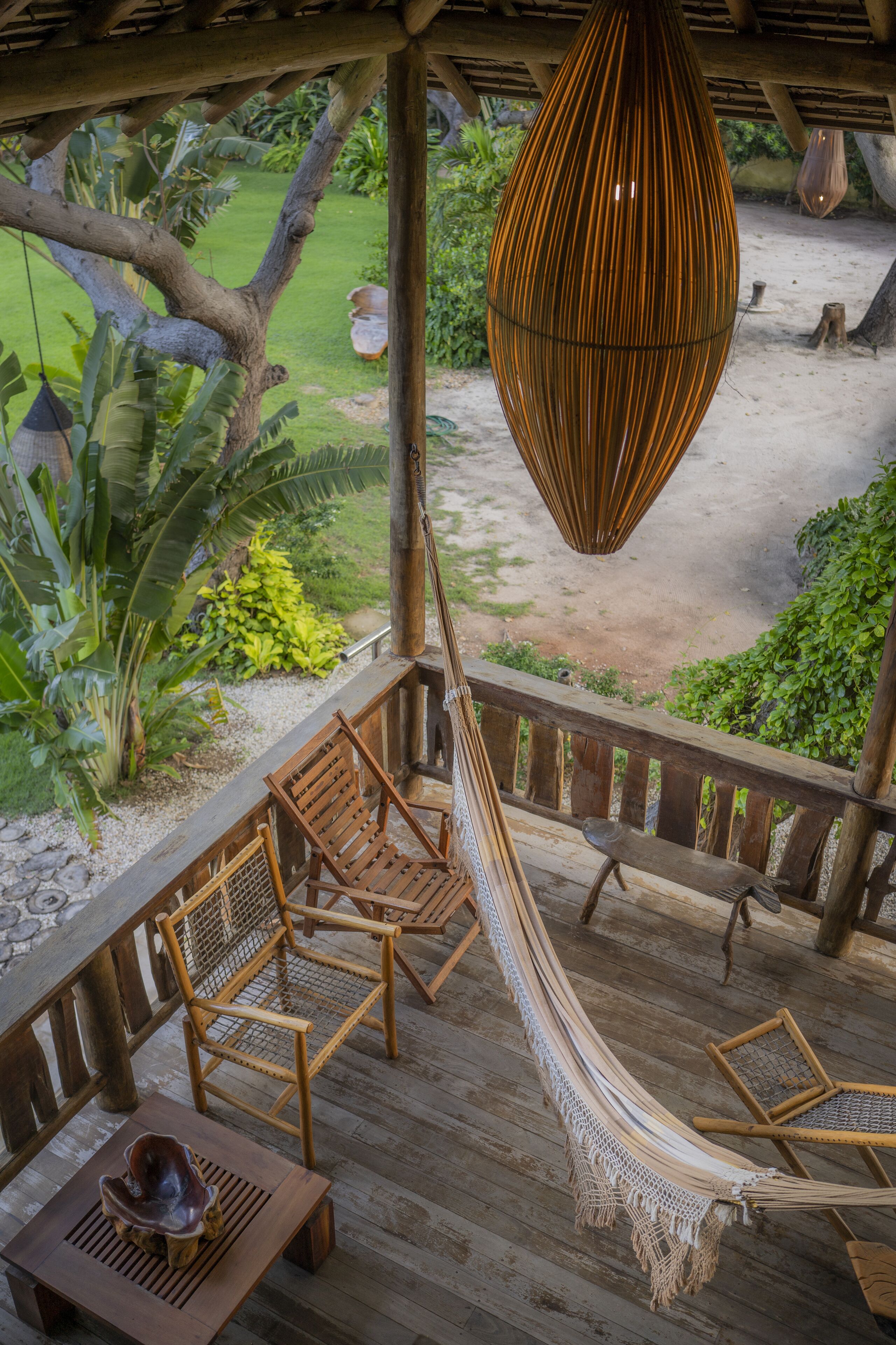 Een houten terras met een hangmat, stoelen en een tafel.