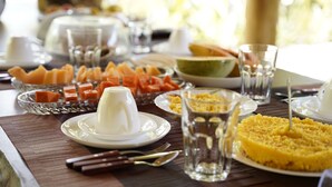 Una mesa servida con varios platos, incluyendo un postre blanco, pastel amarillo y fruta.