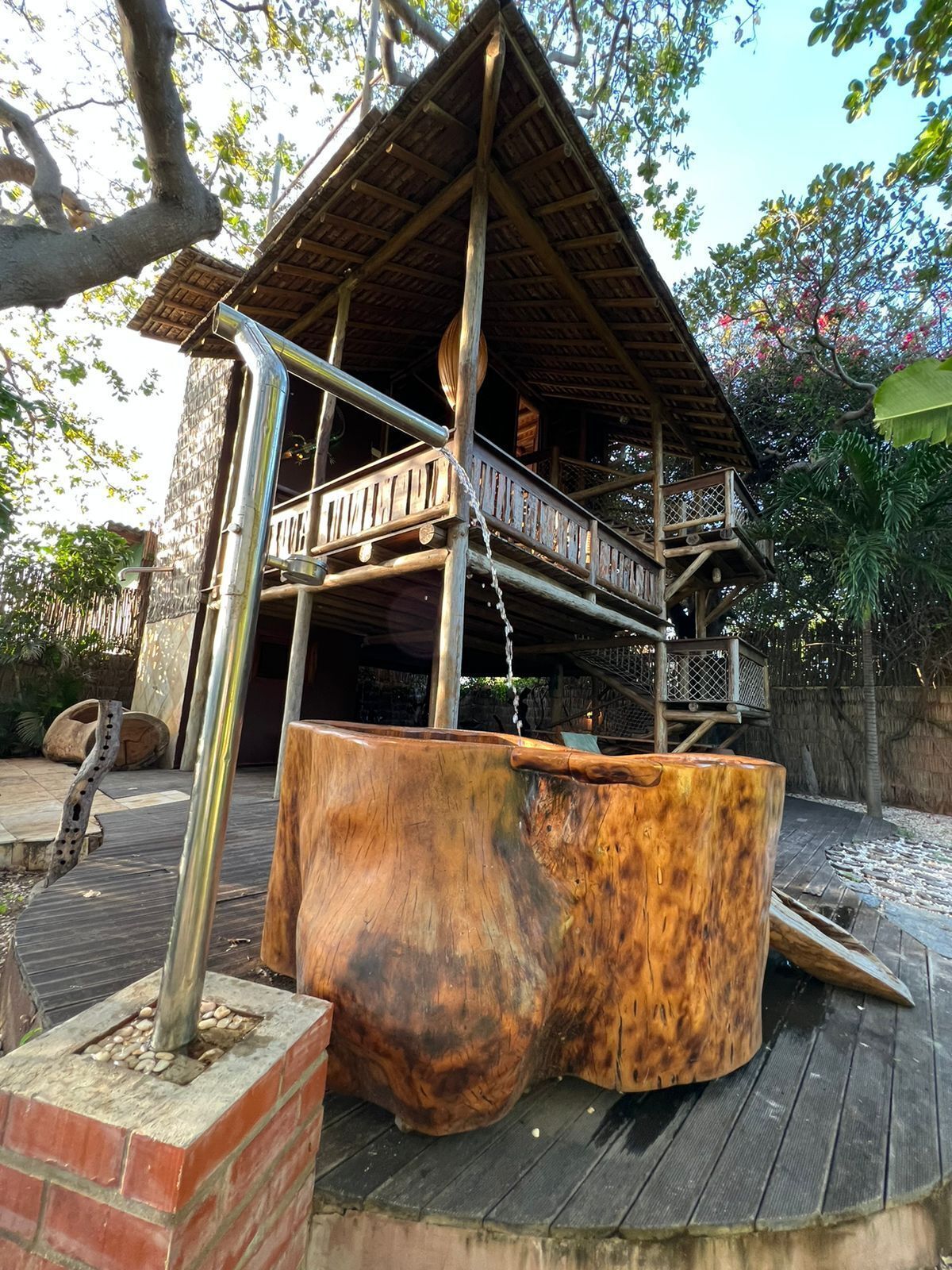 A rustic wooden structure with a metal staircase and a large wooden basin.