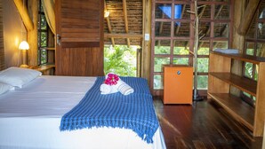 Una habitación de madera con una cama, una mesita y una ventana.