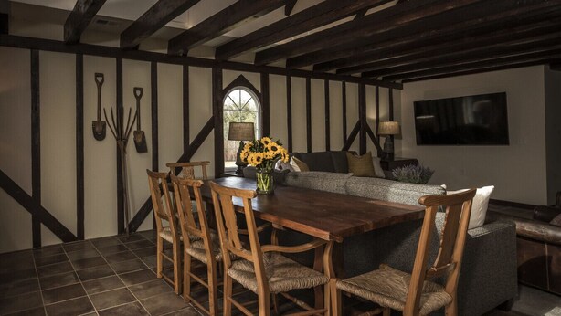 A dining area with a wooden table and chairs, a vase of sunflowers, and a view of the outdoors through a window. - Comissary Middleburg (Huger)