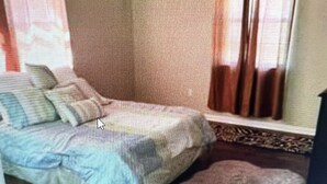 Une chambre à coucher avec un lit, un ventilateur de plafond et une fenêtre avec des rideaux.