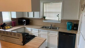 Une cuisine moderne avec des meubles blancs, un four à micro-ondes encastré, un évier et un lave-vaisselle.