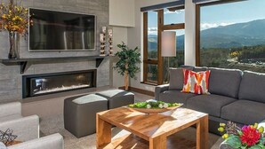 A modern living room with a fireplace, large windows, and a view of mountains.