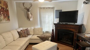 Un salon comprenant un canapé, un téléviseur, une cheminée et une tête de cerf fixée au mur.