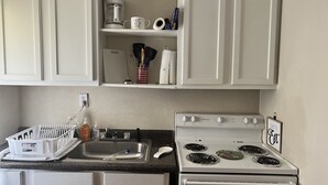 Une cuisine avec des meubles blancs, une cuisinière, un évier et une machine à café.
