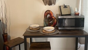 Un coin repas agrémenté d’une tête de cerf fixée au mur, d’un four à micro-ondes et d’une petite table avec des tabourets.